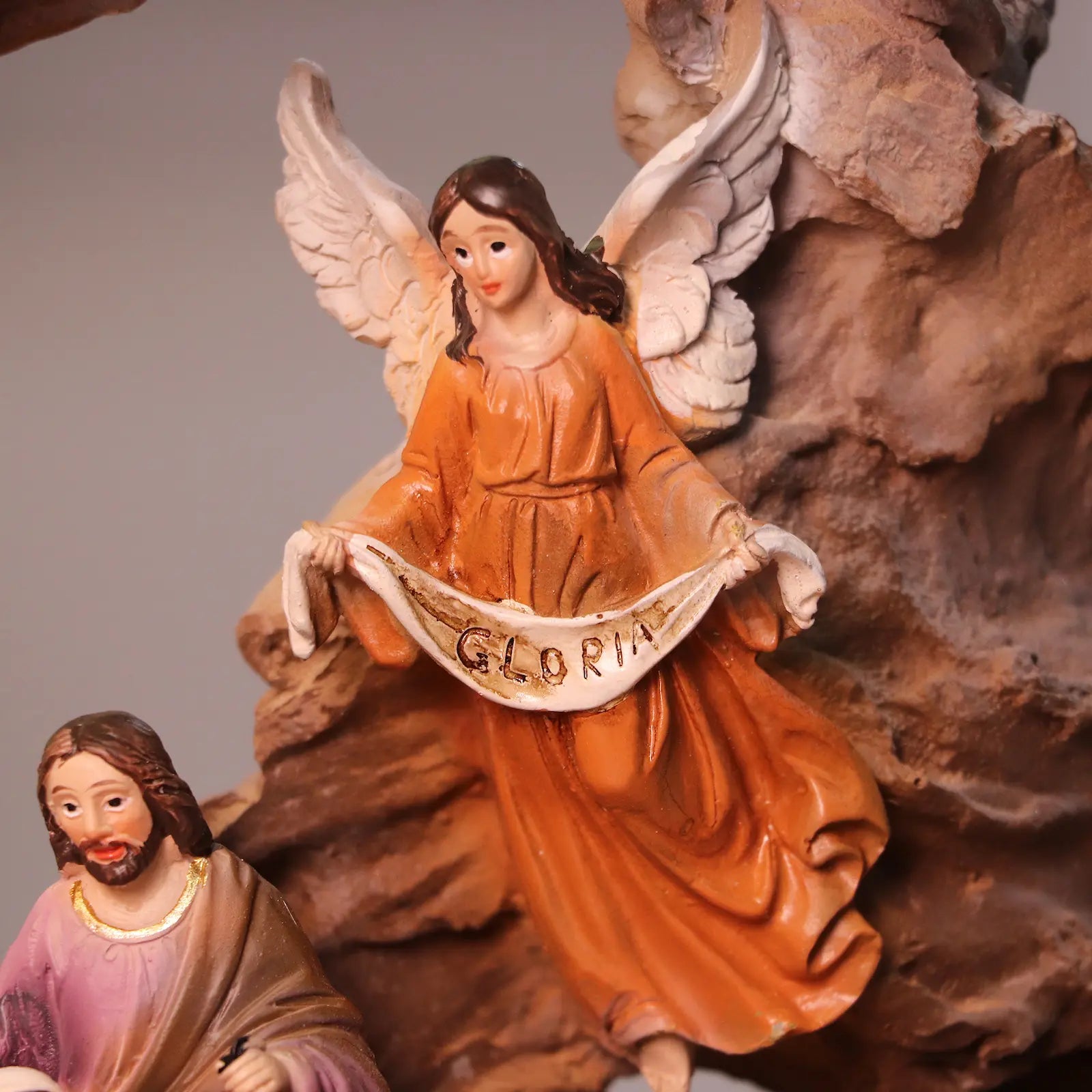 Angel Gloria figurine above Holy Family in illuminated Christmas manger display