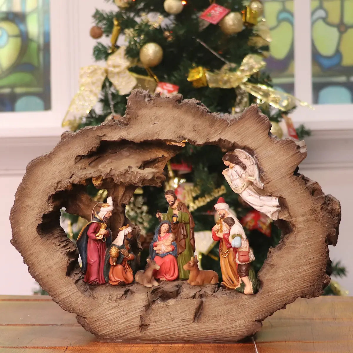 Rustic illuminated nativity scene with Holy Family figurines inside a log-style stable Christmas decoration