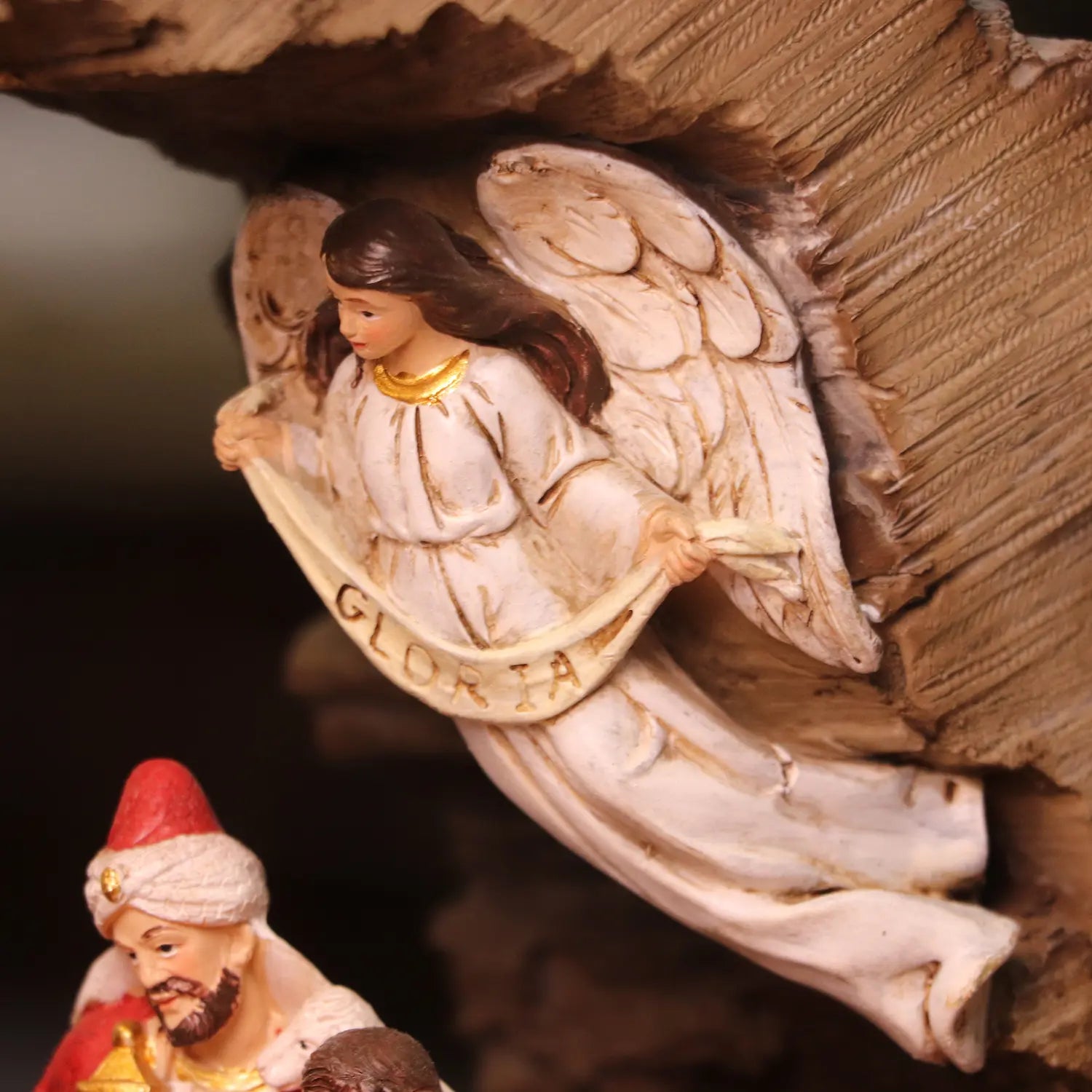 White angel figurine with wings overlooking Christmas nativity scene inside rustic stable