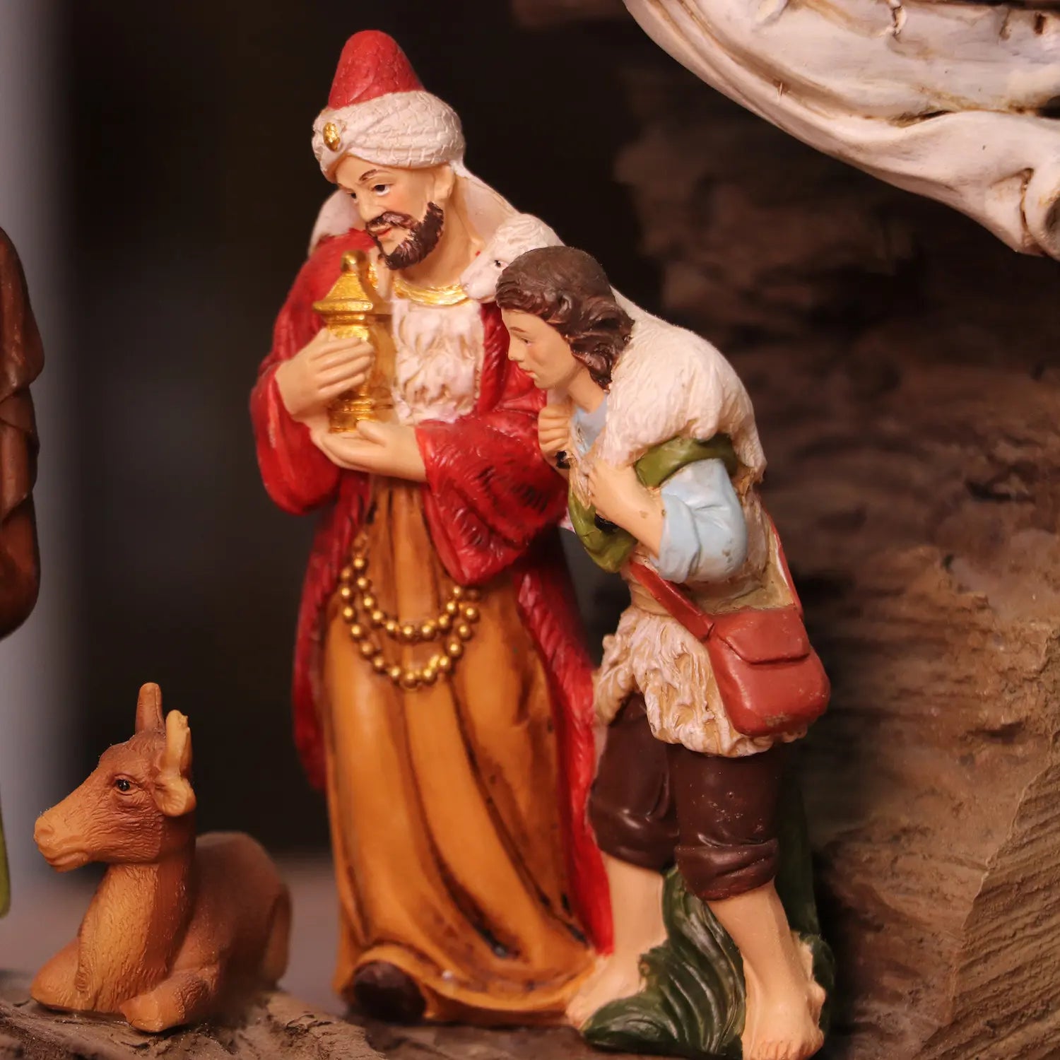 Shepherd and Wise Man figurines with gifts beside animals in Christmas manger decoration