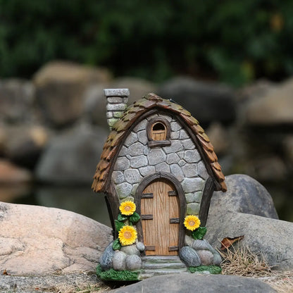 Solar sunflower fairy house displayed in garden among rocks and natural stone backdrop