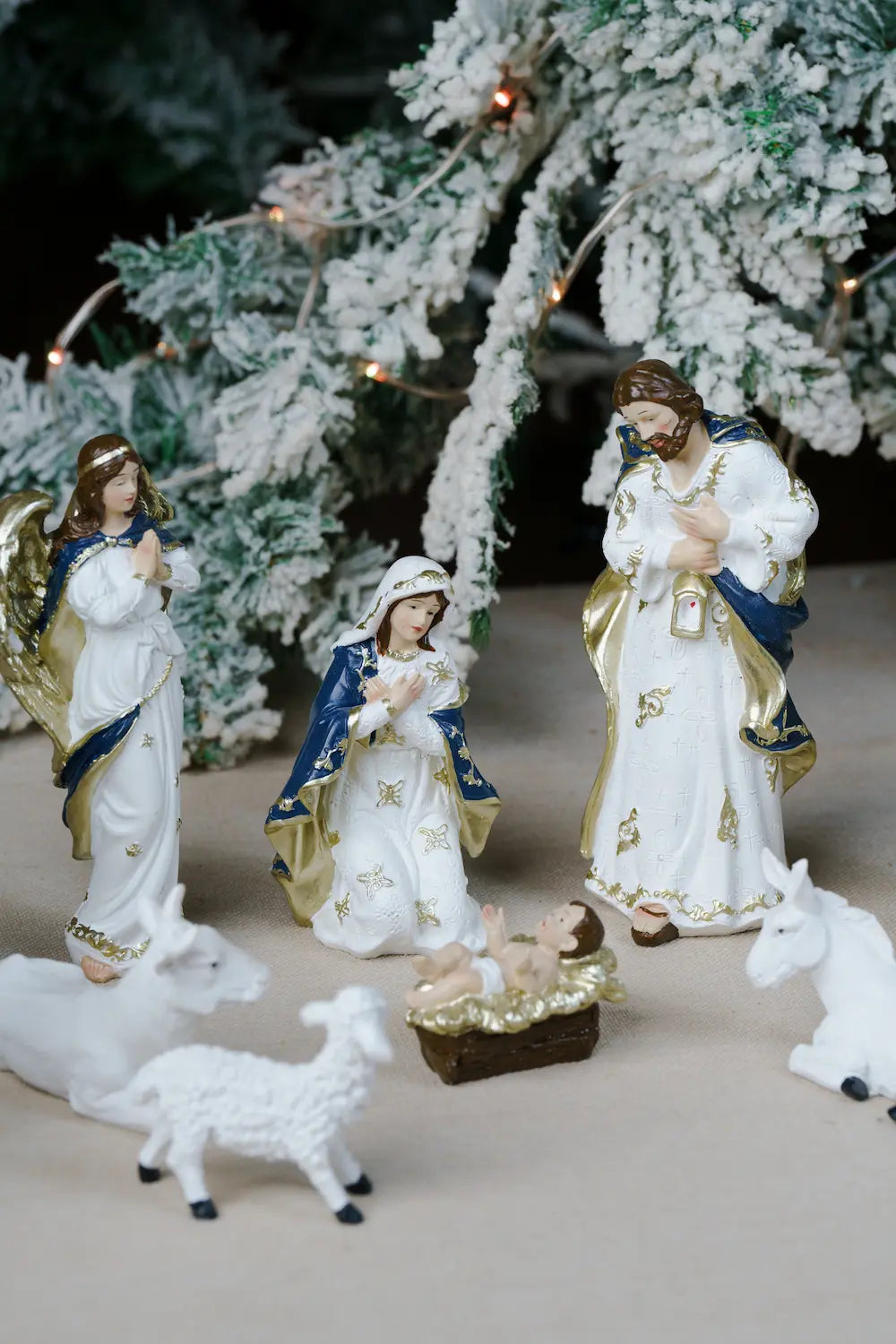 A Christmas nativity scene figurine set featuring Mary, Joseph, baby Jesus in a manger, an angel, and stable animals.