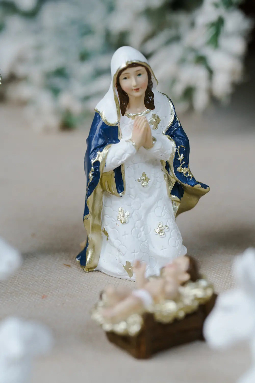 A small figurine of the Virgin Mary kneeling beside baby Jesus in a manger.