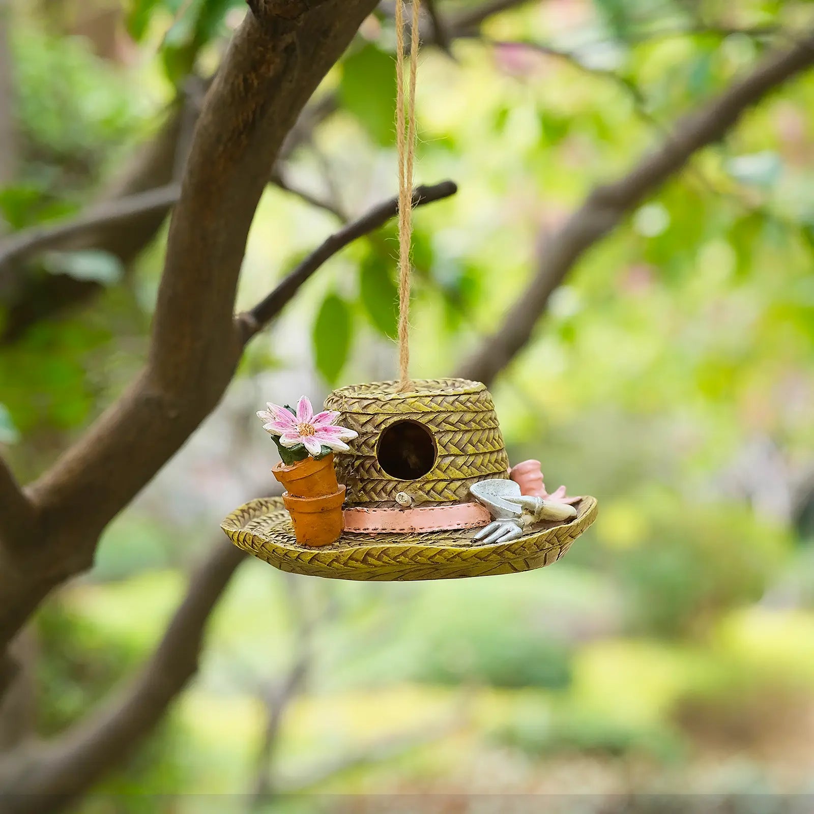 Garden hat birdhouse with flower pot hanging from tree branch