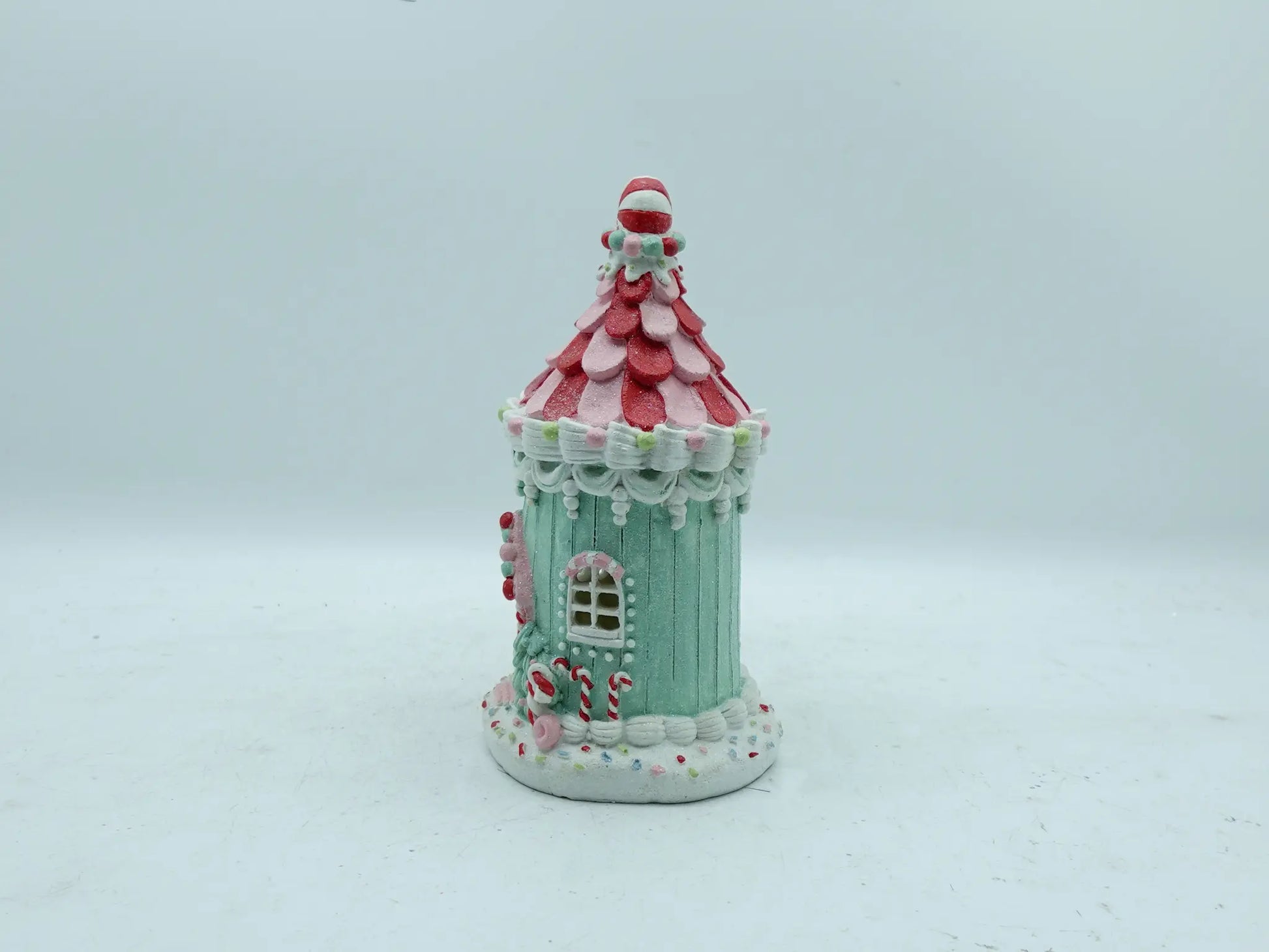 Side view of hand-painted candyland gingerbread house figurine with mint-green walls and peppermint candy roof