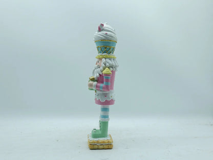 A decorative nutcracker figurine painted in pastel colors, standing on a light gray background, left side view .