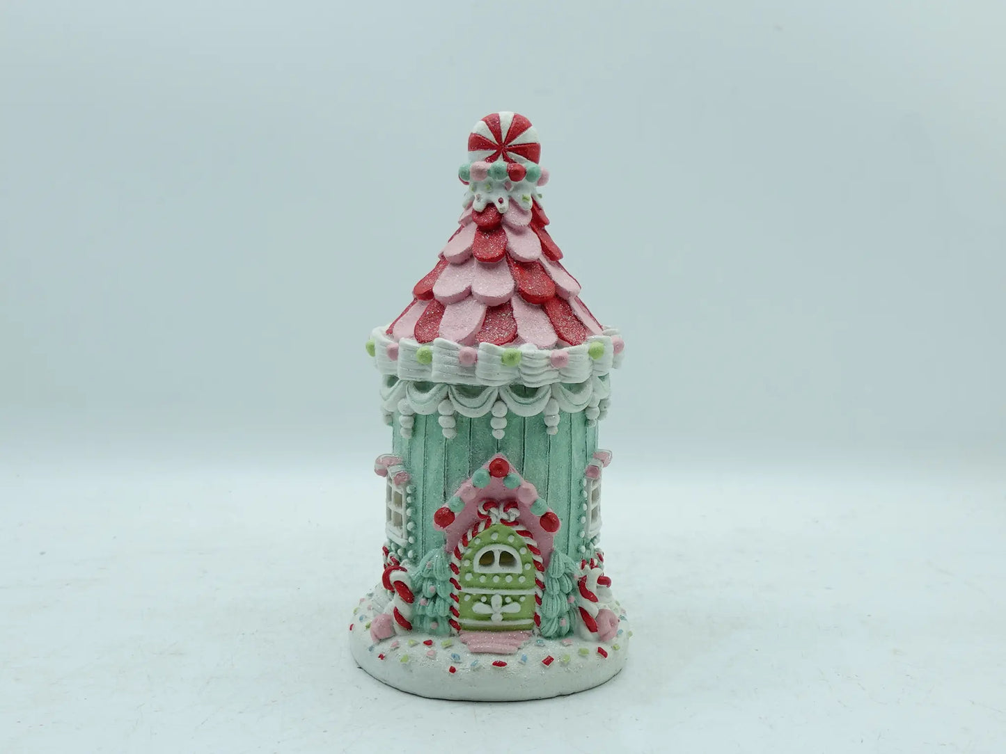 A decorative gingerbread house ornament with a pastel mint green body, photographed against a plain light gray background.