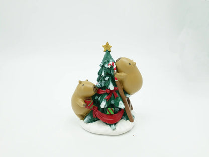 the capybara duo decorating tree figurine showing the tree branches, ribbon details, and snowy base from behind