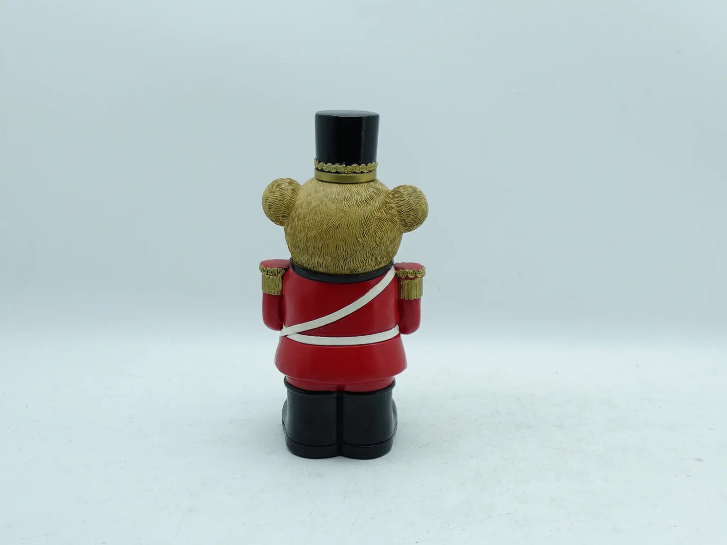 the teddy bear drummer figurine showing the red uniform, white cross strap, and textured bear fur, back view
