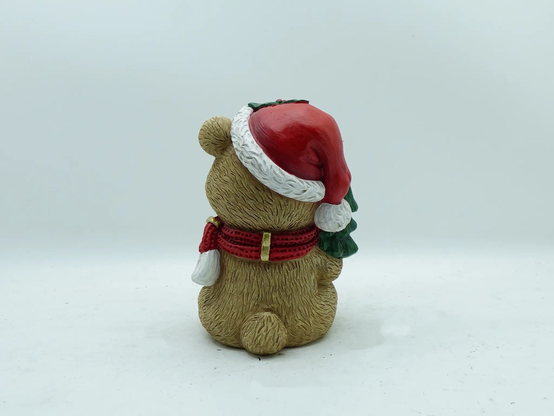 the teddy bear figurine showing the Santa hat pom-pom, scarf ends, and textured fur, back view 
