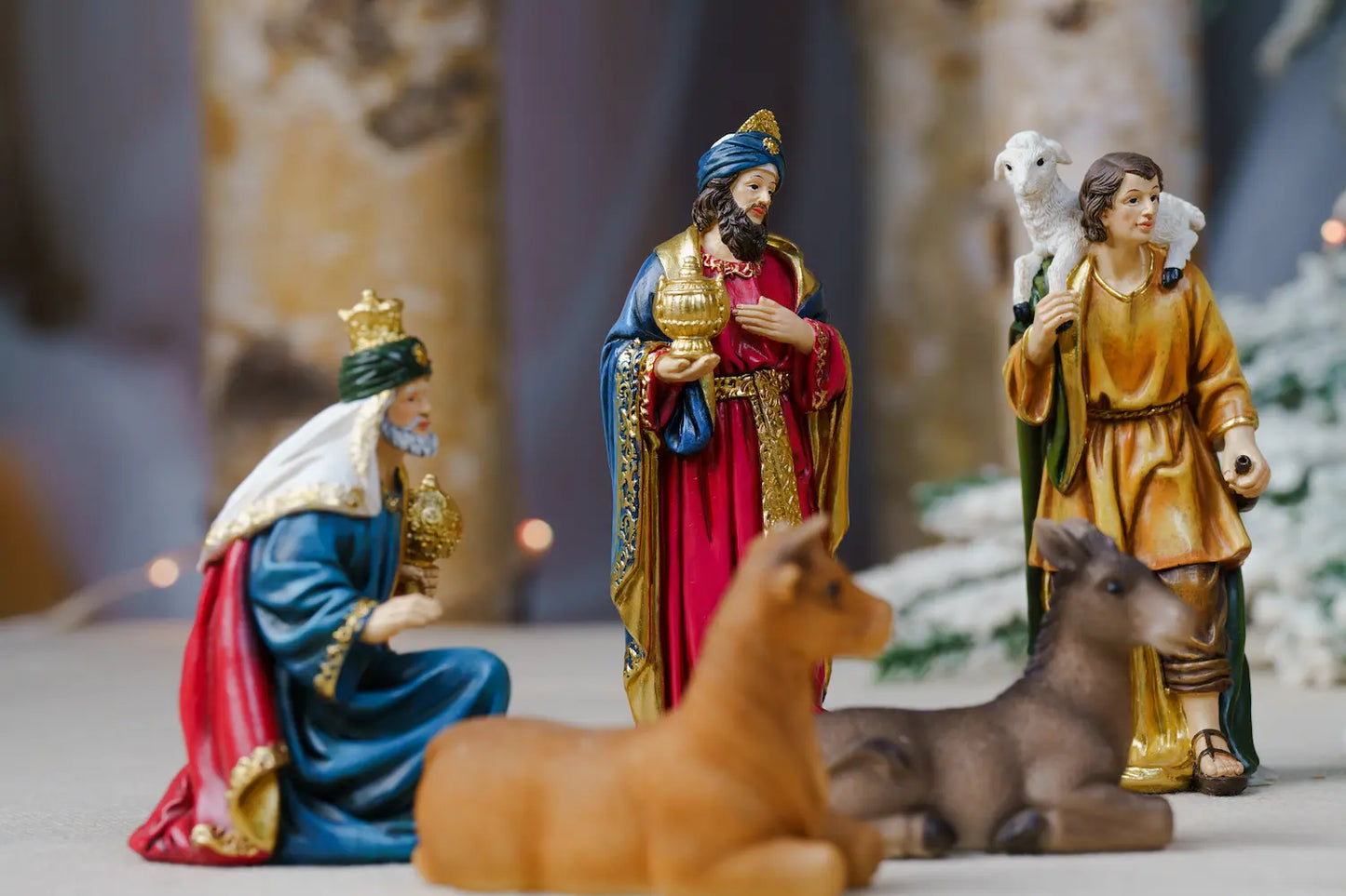A colorful Christmas nativity scene figurine set featuring Mary, Joseph, the Three Wise Men, a baby Jesus in a manger, and animals including a donkey, sheep, and calf.