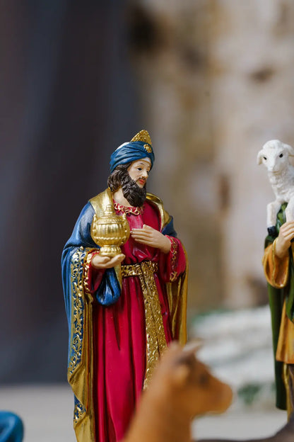 a nativity figurine depicting the Wise Men, with one figure in a red robe and blue turban holding a gold lamp.