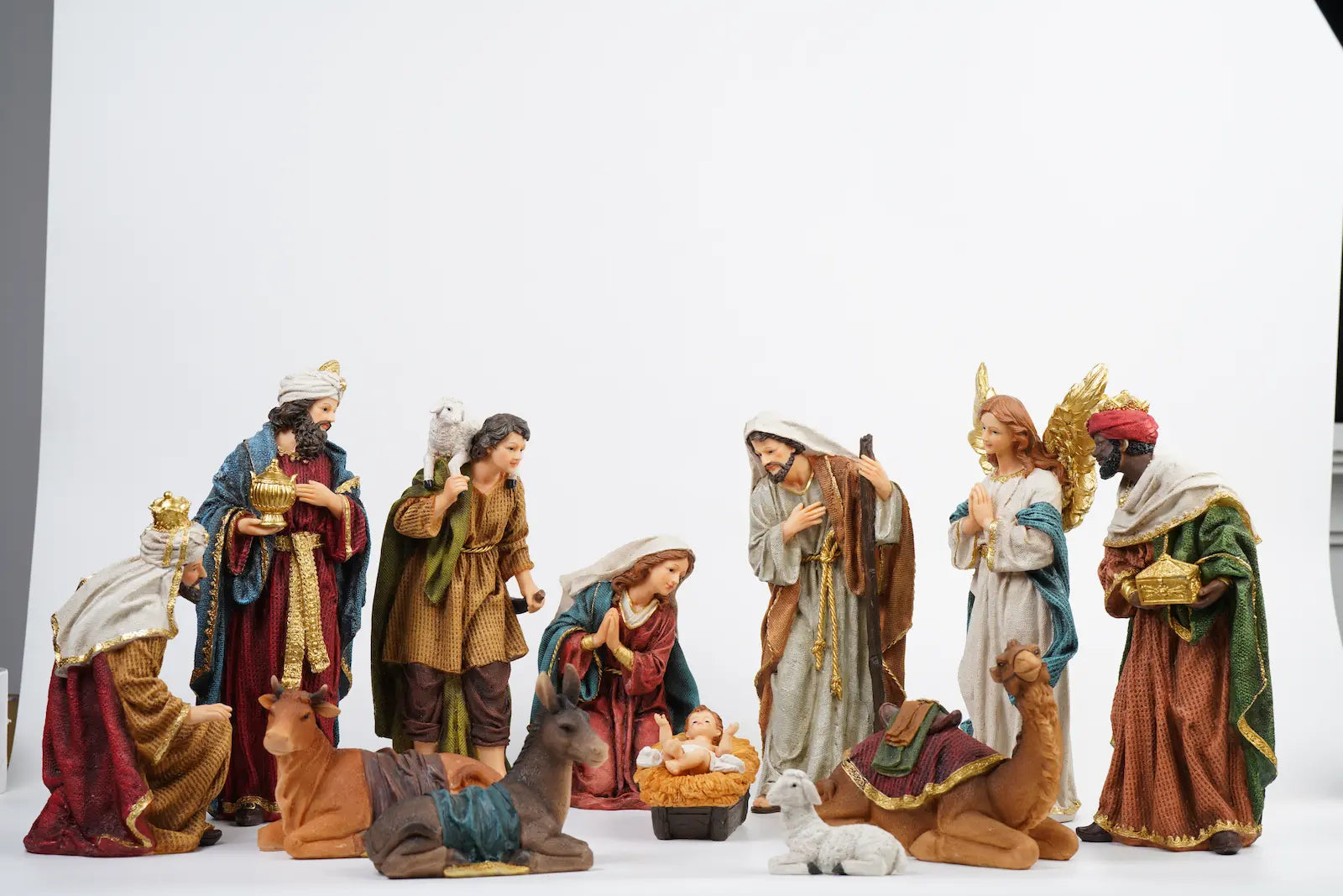 Complete 12-piece colorful nativity scene on white studio background showing full crèche arrangement