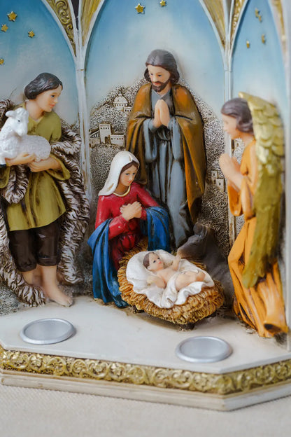 Hand-painted nativity scene figurine set with Mary, Joseph, baby Jesus in a manger, an angel, and a shepherd holding a lamb.