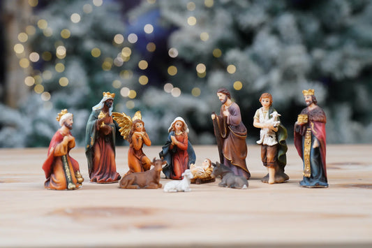 Pocket-size nativity figurines arranged on wooden surface, mantel and shelf Christmas decor.