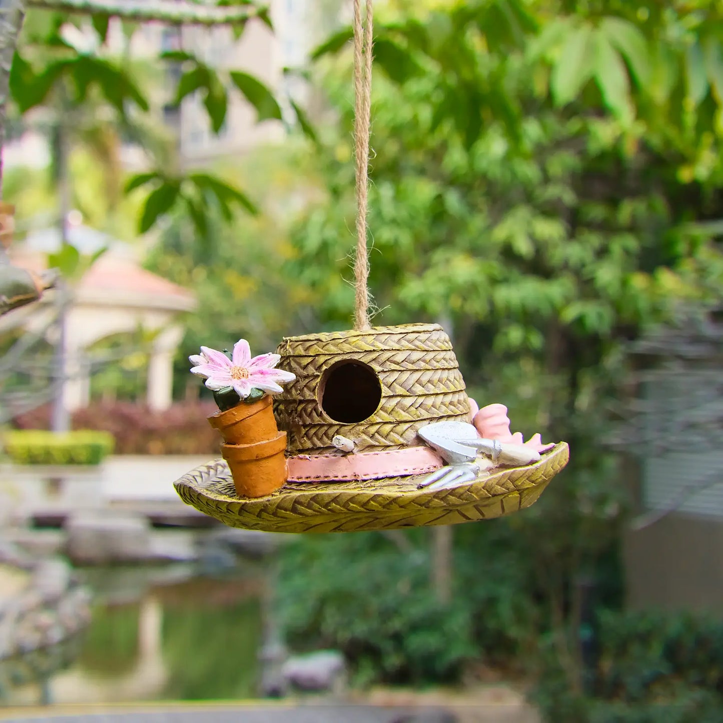 Garden hat birdhouse hanging outdoors near pond and trees