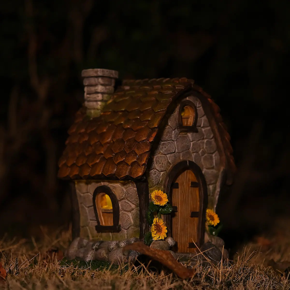 Stone cottage fairy house with sunflowers glowing at night side view warm window light