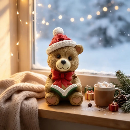 the teddy bear reading book figurine displayed on a windowsill with fairy lights, hot cocoa, blanket, and snowy window view