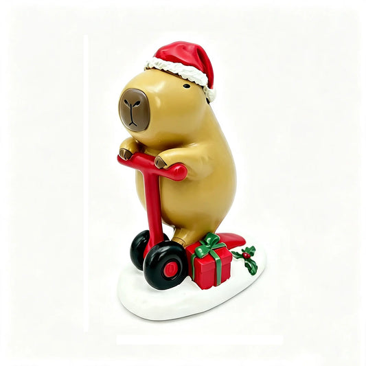 A Christmas capybara figurine wearing a red Santa hat and riding a red scooter, with a red gift box and green holly on a white base