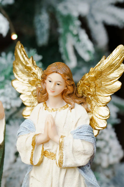 A praying angel figurine with large metallic gold wings, brown hair, and a cream robe with blue and gold accents.