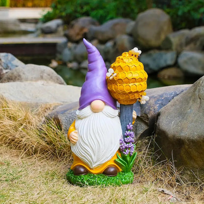 Bee-themed garden gnome statue displayed outdoors near rocks and pond