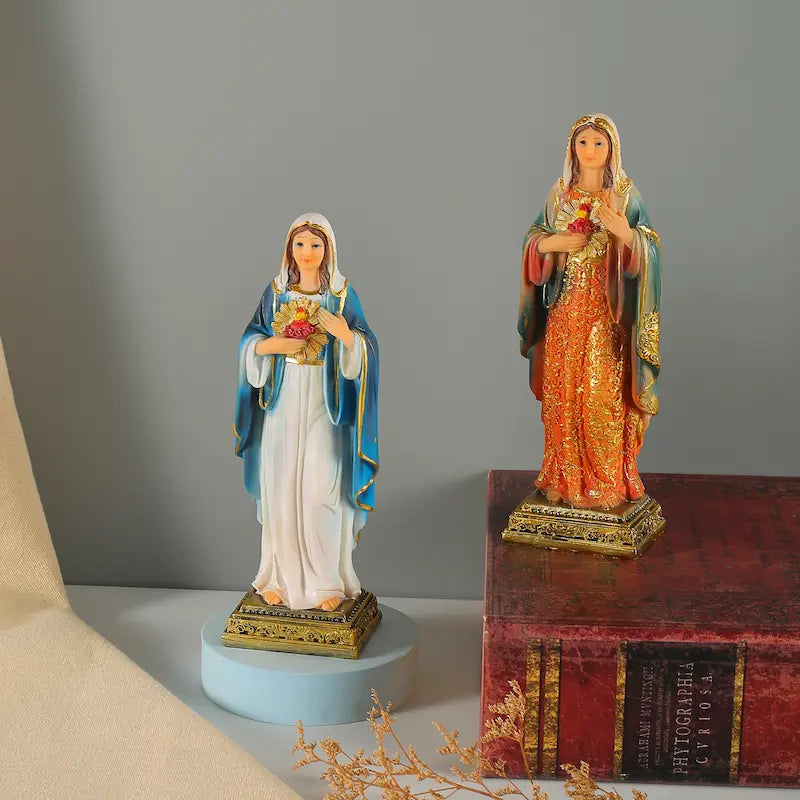 Two religious statues on a gray background with a book and decorative elements.