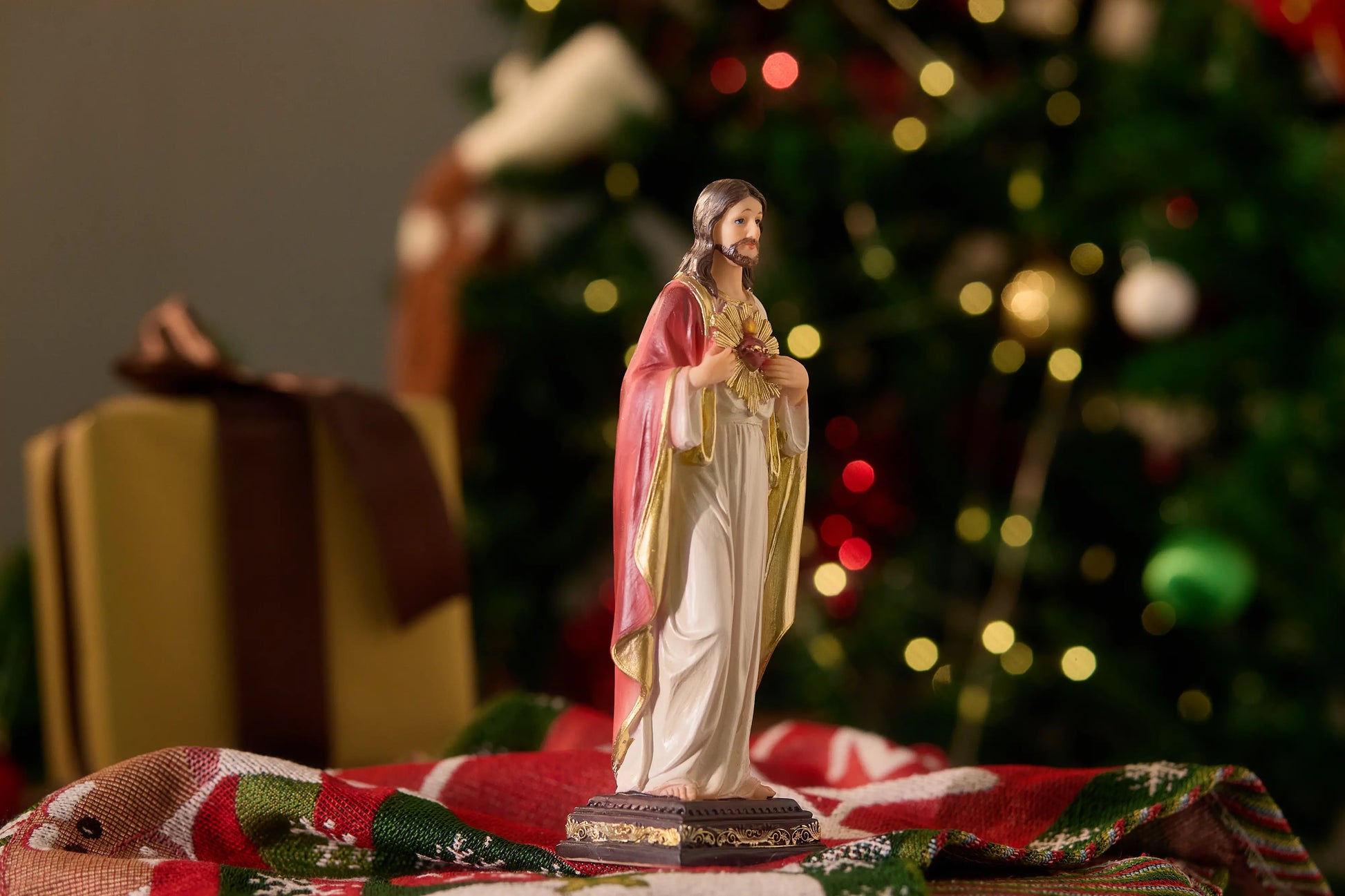 Religious Jesus Christ figurine near Christmas tree and gift boxes