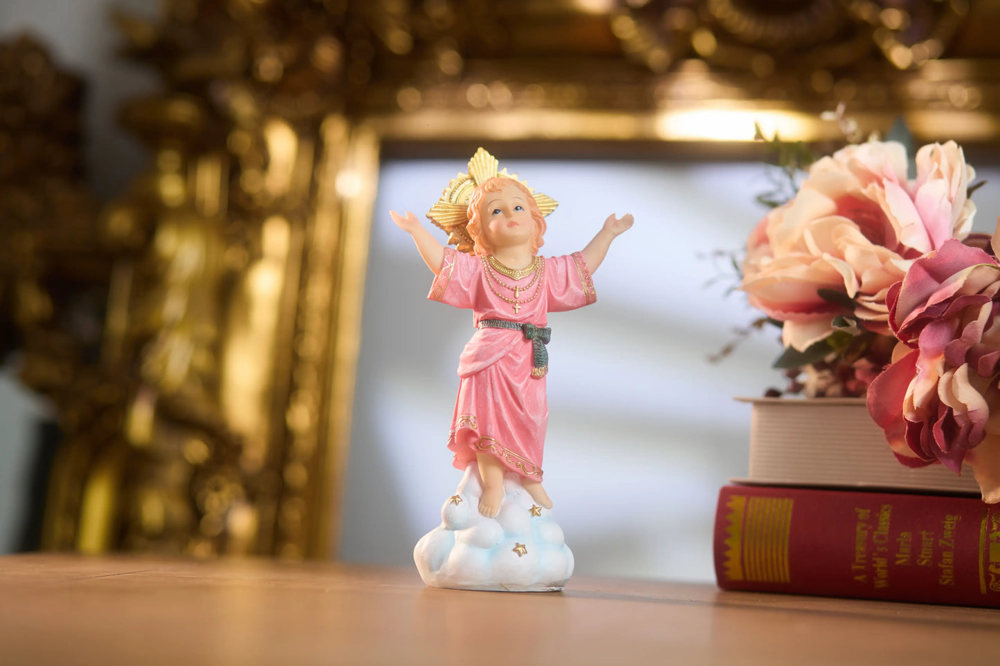 Divine Child statue showing gold rosary necklace, cross pendant, and pink robe trim