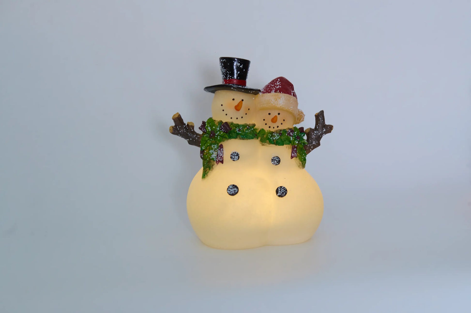 Lighted snowman couple figurine with warm LED glow on grey background 
