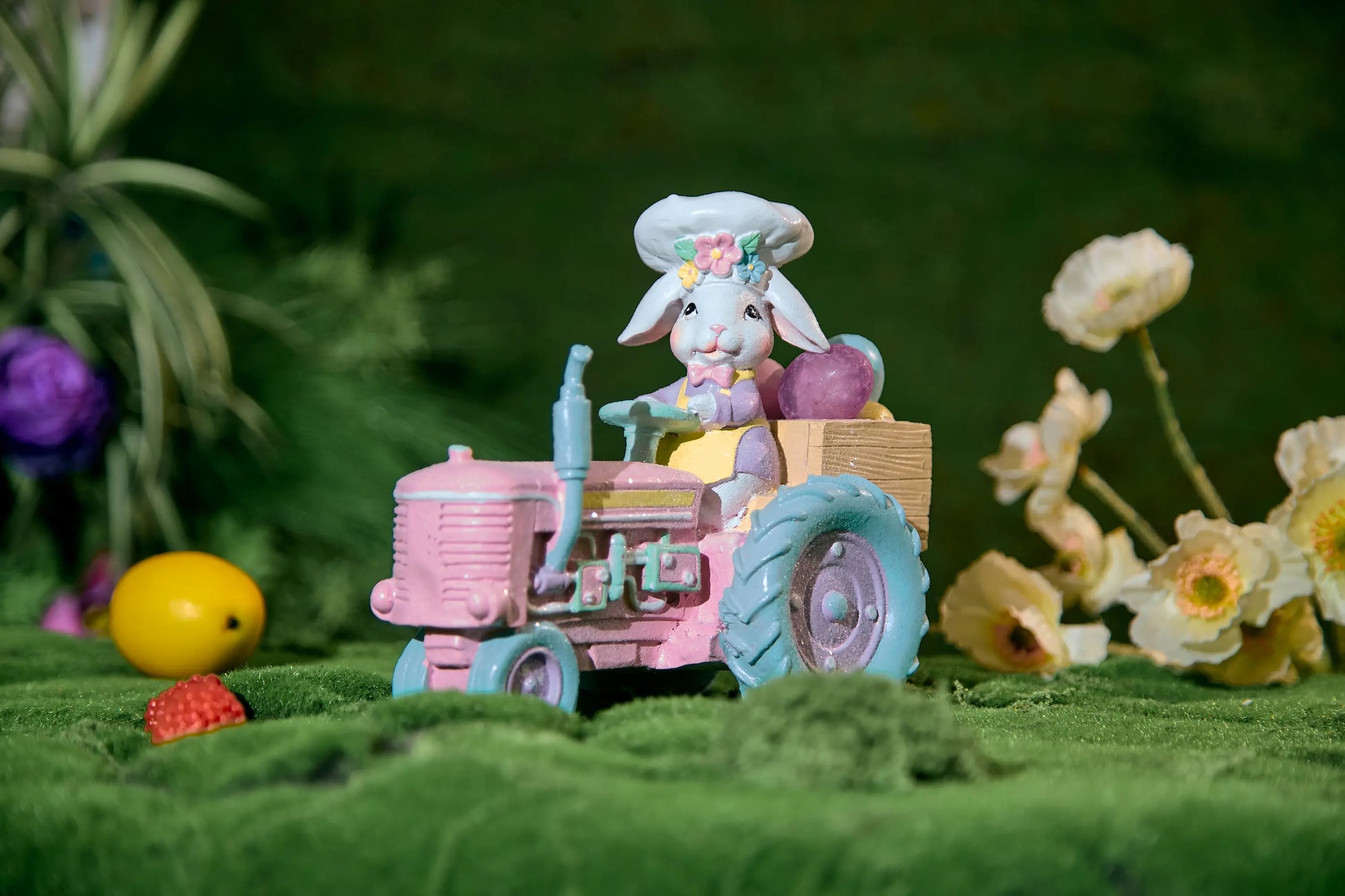 Pastel Easter bunny chef tractor figurine on moss surface with spring flowers and Easter eggs — glitter resin farmhouse spring decoration