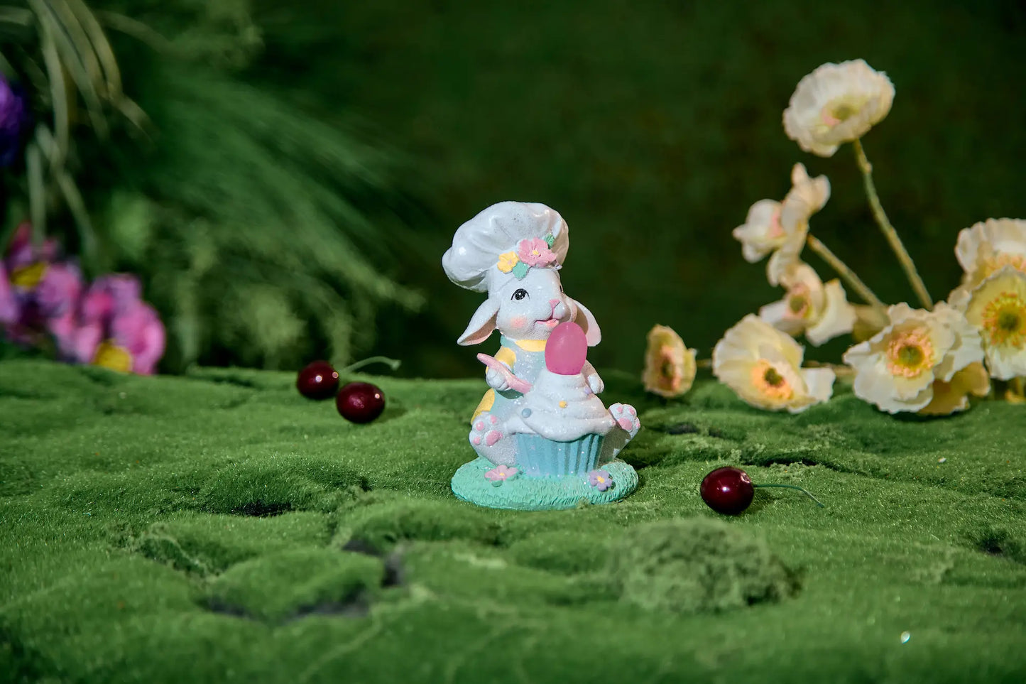 Hand-painted resin bunny cupcake figurine in garden setting