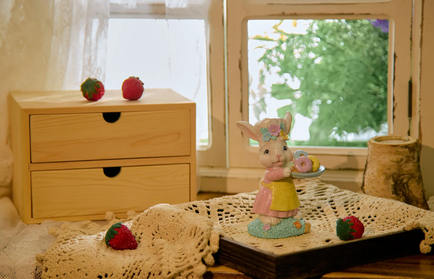 Easter bunny figurine on lace doily beside window with wooden drawer unit — pastel spring decoration in cottagecore interior vignette