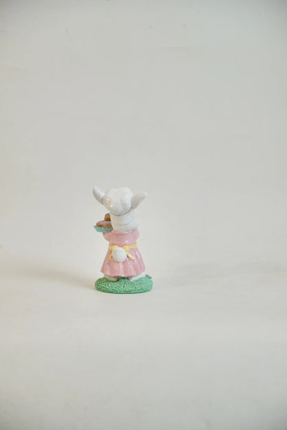 Rear view of Easter bunny figurine showing white cotton tail, yellow sash, and pink ruffled hem — glitter resin spring tabletop accent