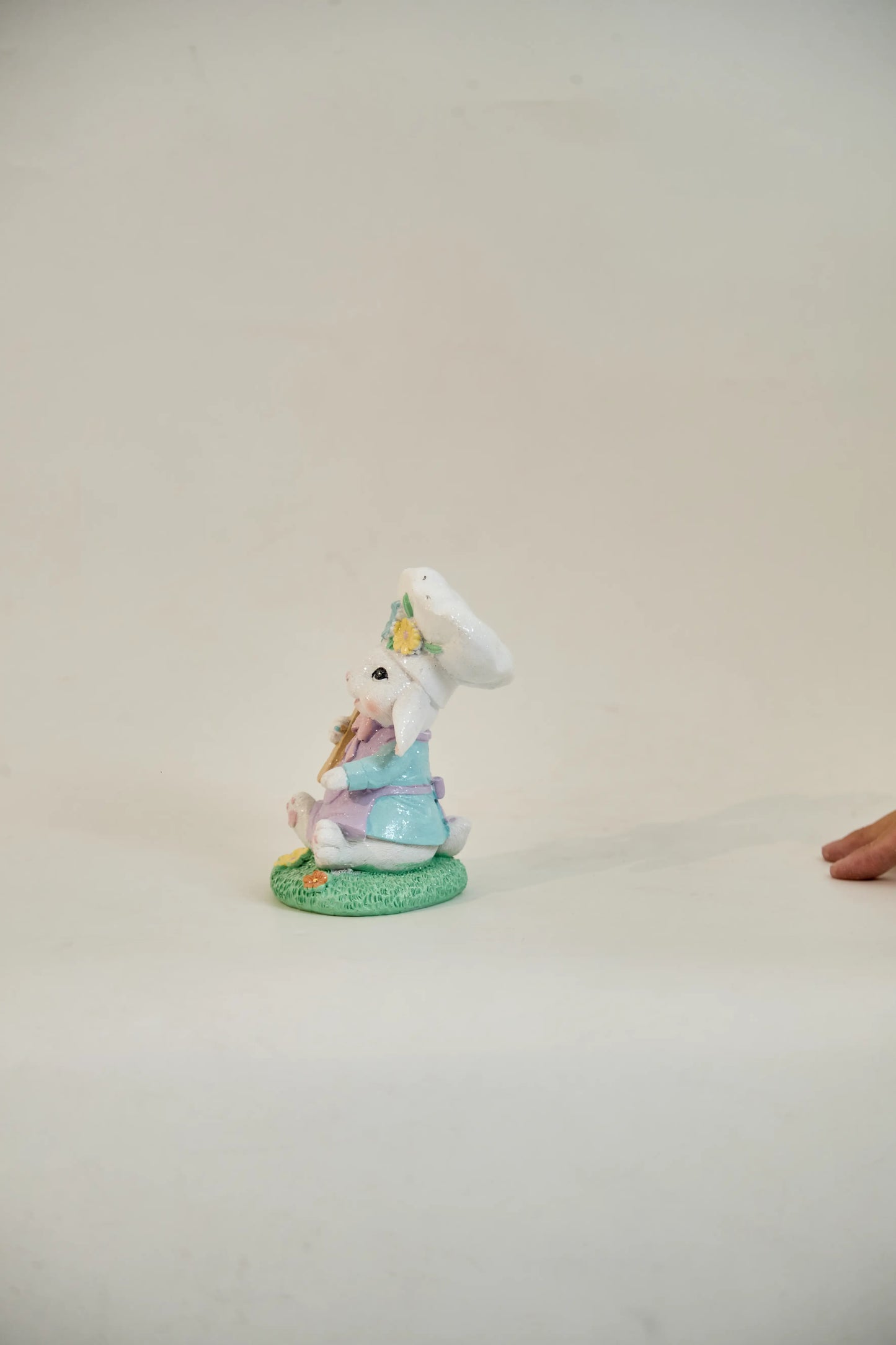 Side profile of Easter bunny chef figurine showing lop ears, chef toque, and grassy base — hand-painted glitter resin spring decoration
