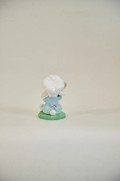 Rear view of Easter bunny chef figurine showing lavender apron bow, sky-blue outfit, and white cotton tail — glitter resin spring tabletop accent