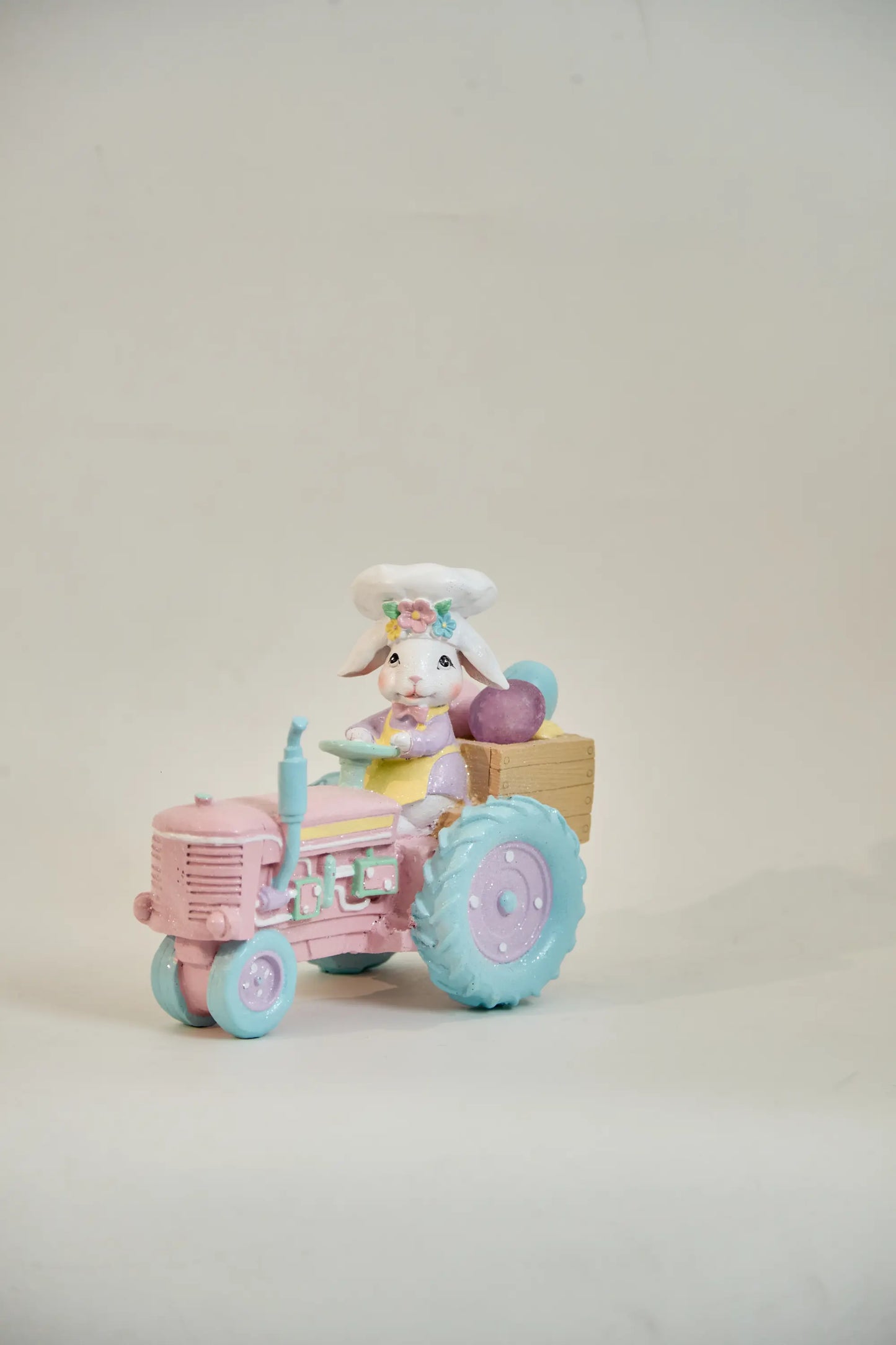 Zayton pink tractor Easter bunny figurine front view — hand-painted glitter resin spring tabletop accent on neutral studio background