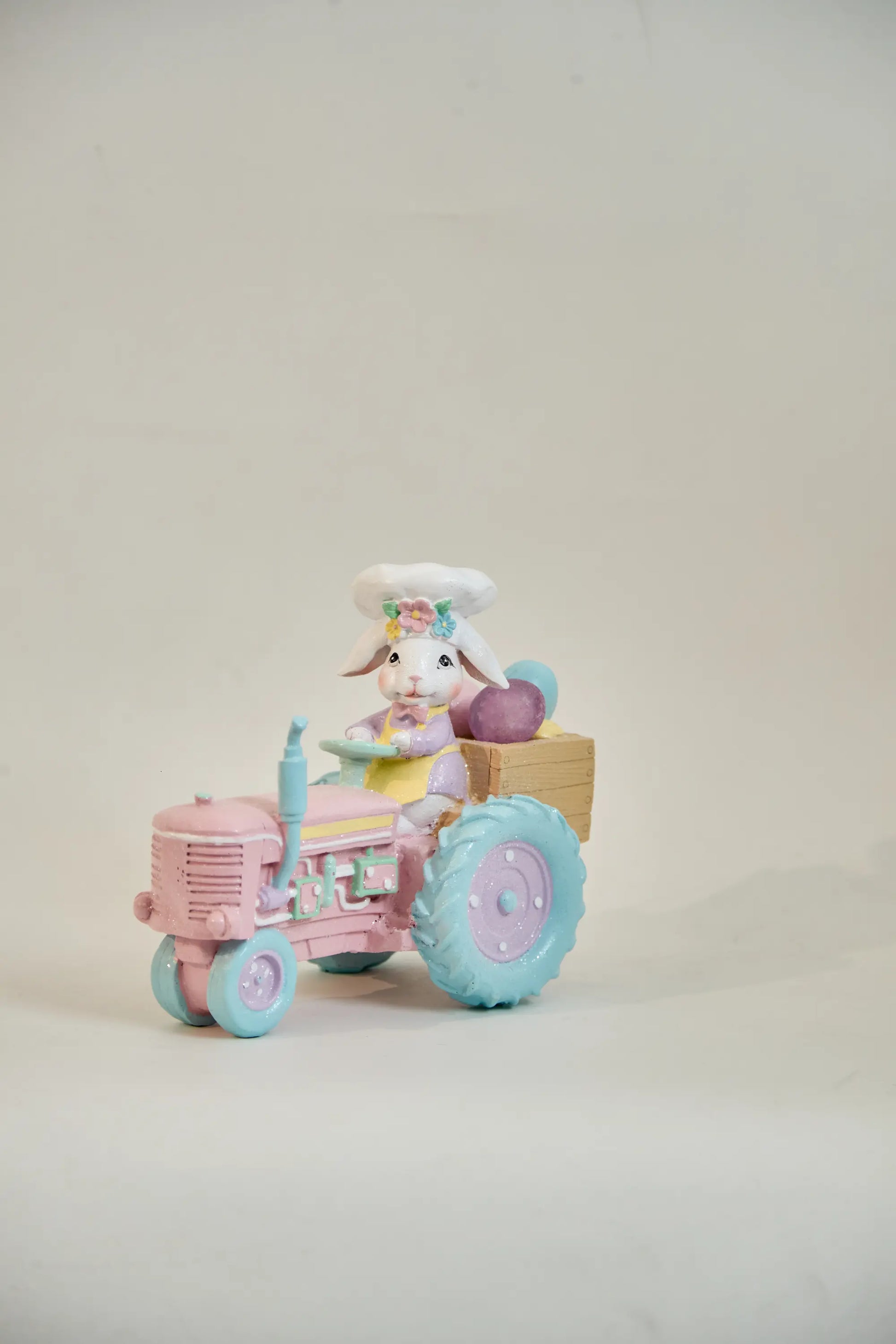 Zayton pink tractor Easter bunny figurine front view — hand-painted glitter resin spring tabletop accent on neutral studio background