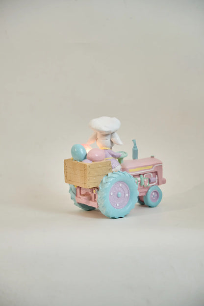 Rear view of Easter bunny tractor figurine showing full egg cargo crate with LED glow and blue tractor wheels — hand-painted glitter resin spring décor
