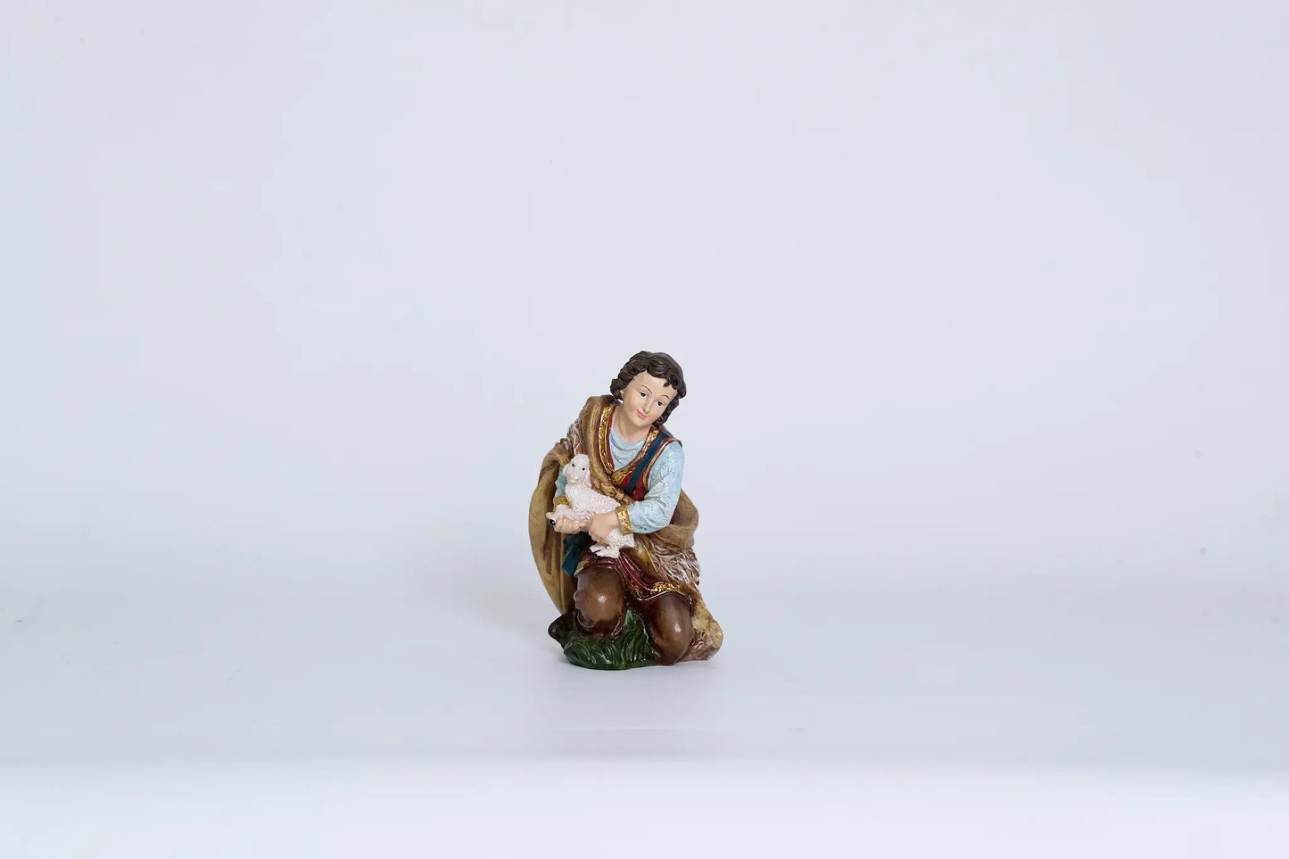 Shepherd holding lamb figurine close-up, nativity shepherd figure for creche display.