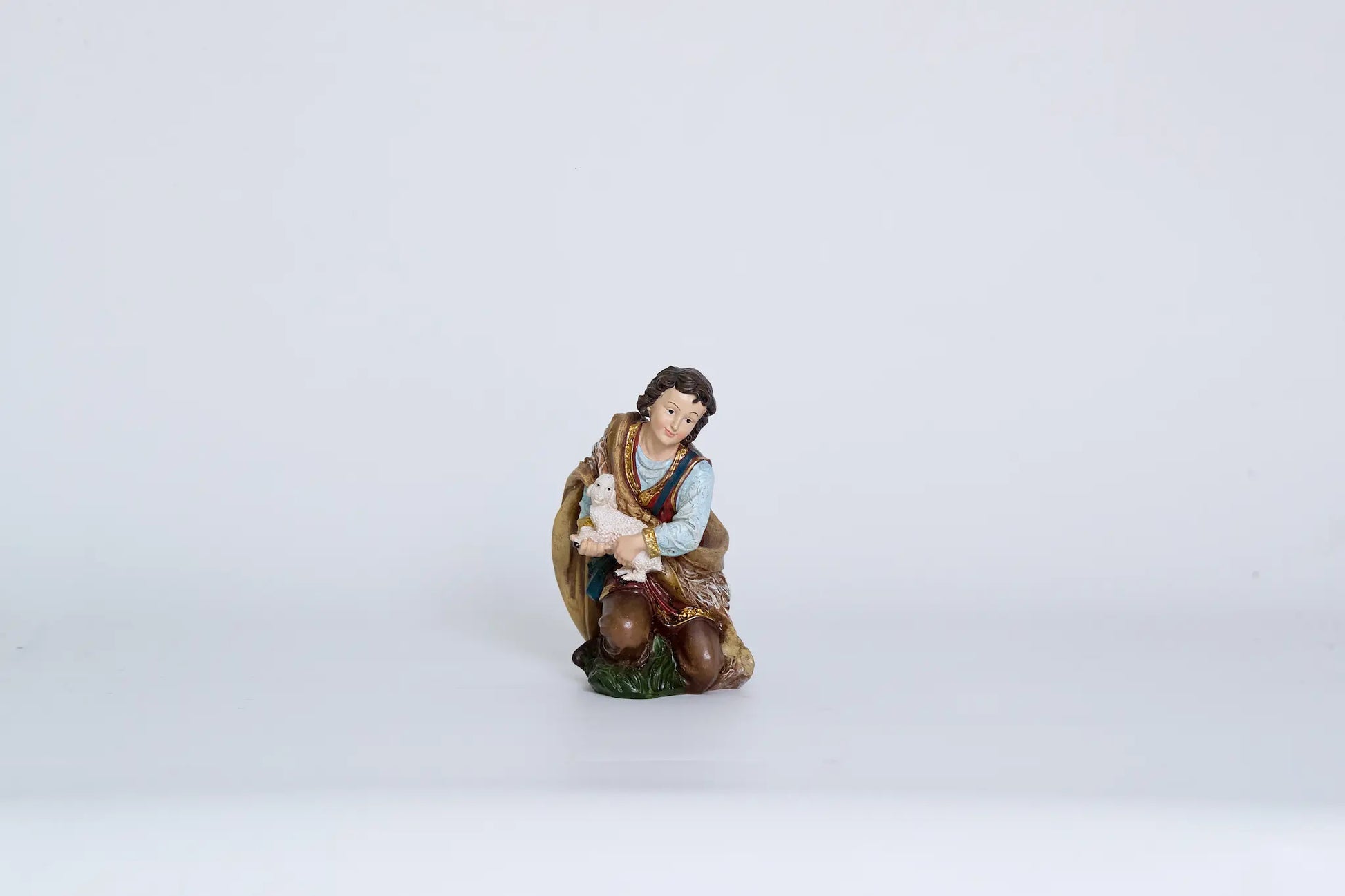 Shepherd holding lamb figurine close-up, nativity shepherd figure for creche display.