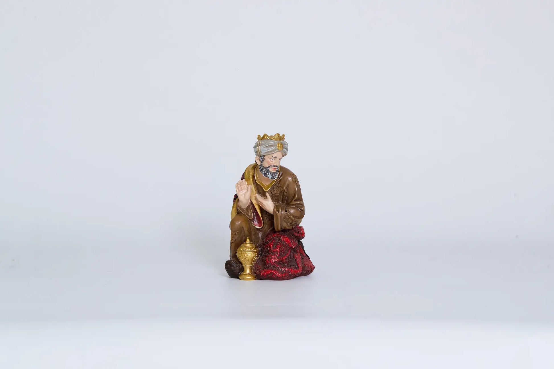 Kneeling Wise Man with gift vessel, nativity Magi figurine on white background.