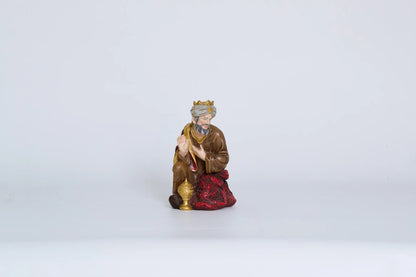 Kneeling Wise Man with gift vessel, nativity Magi figurine on white background.