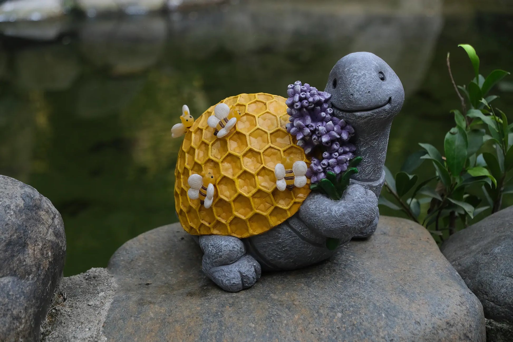 Turtle garden figurine with bees and honeycomb shell displayed near pond and rocks
