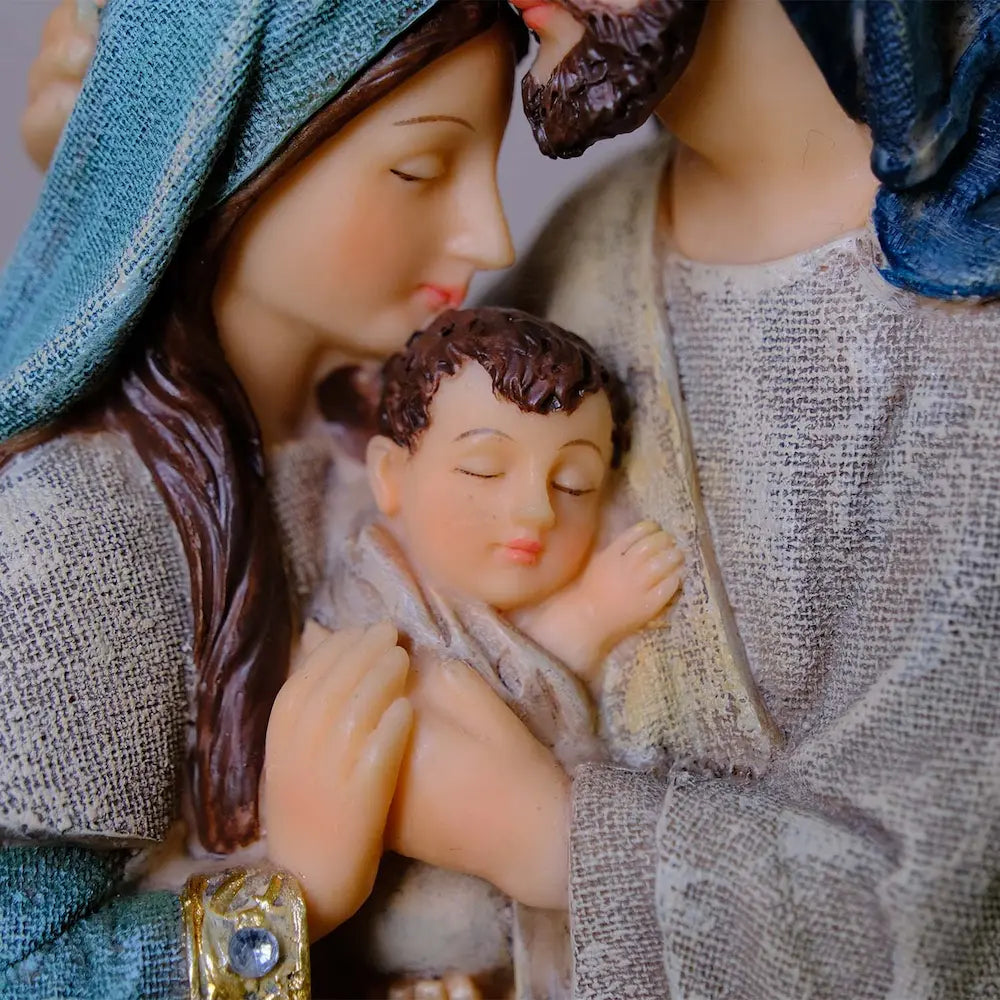 Baby Jesus close-up in Holy Family statue — swaddled infant face and hands detail, hand-painted resin figurine
