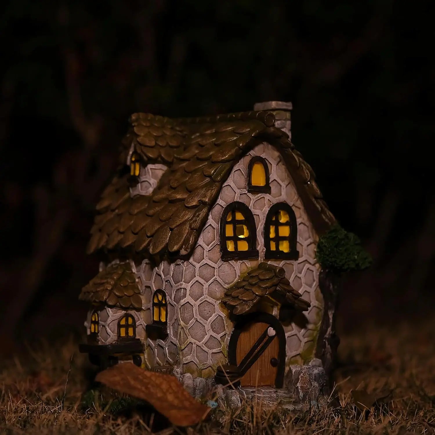 Stone cottage fairy house glowing at night with warm amber windows