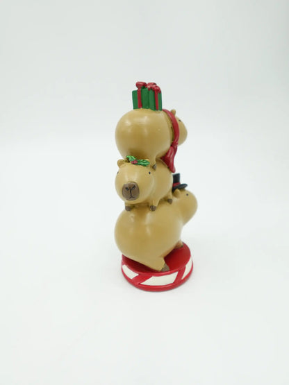 three stacked capybaras figurines showing the vertical totem silhouette and candy-cane striped circular base
