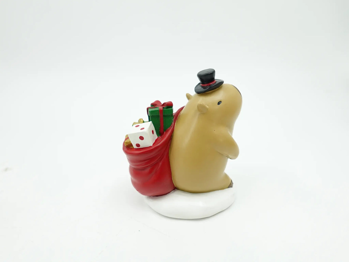 Christmas capybara figurine in top hat carrying a red gift sack on a snow base