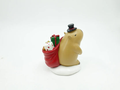 Christmas capybara figurine in top hat carrying a red gift sack on a snow base