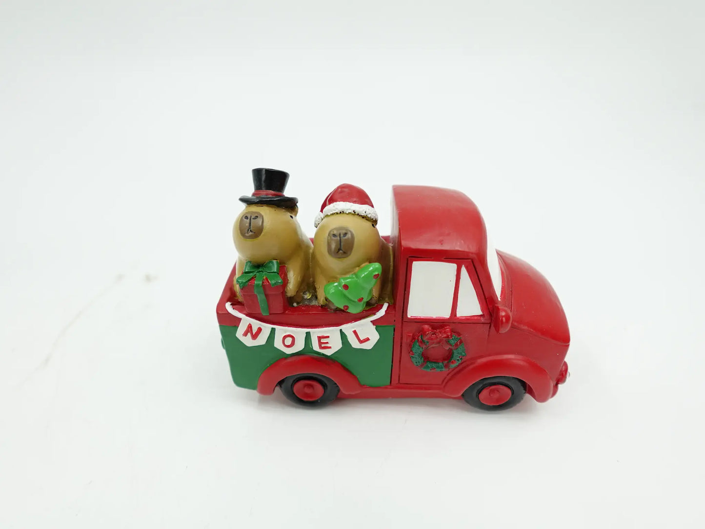 the Christmas capybara couple figurines riding in the truck bed with top hat, Santa hat, gift, and tree