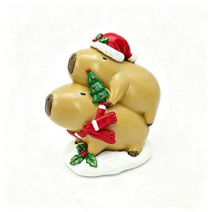 Hand-painted Christmas capybara stacking duo on white background, one in Santa hat with holly holding a mini tree, the other with a red candy-cane striped scarf on a snowy base